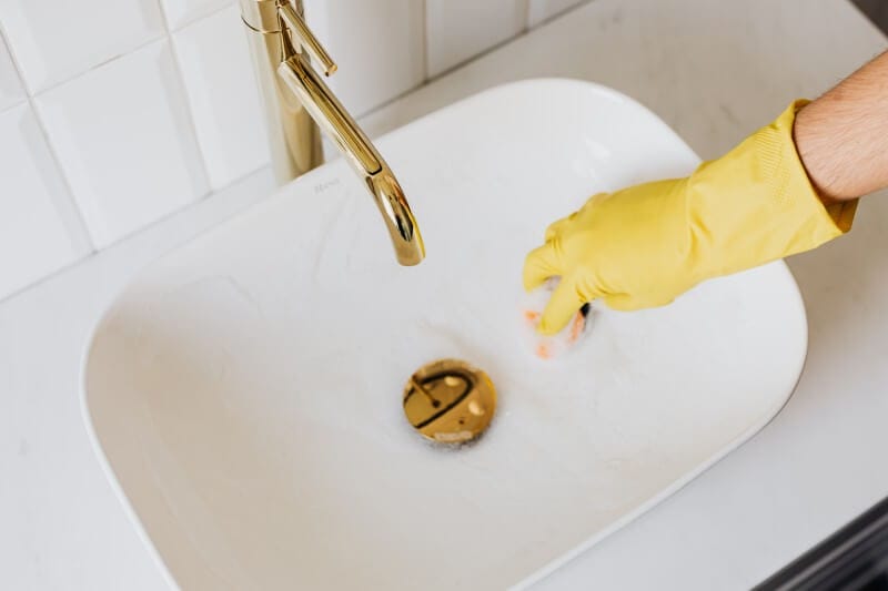 person in glove cleaning sink