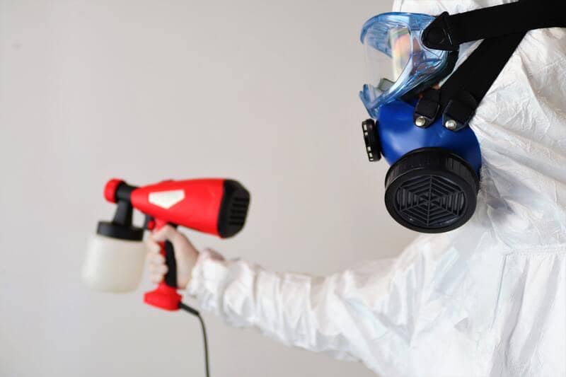 pest control expert spraying chemical to kill roaches